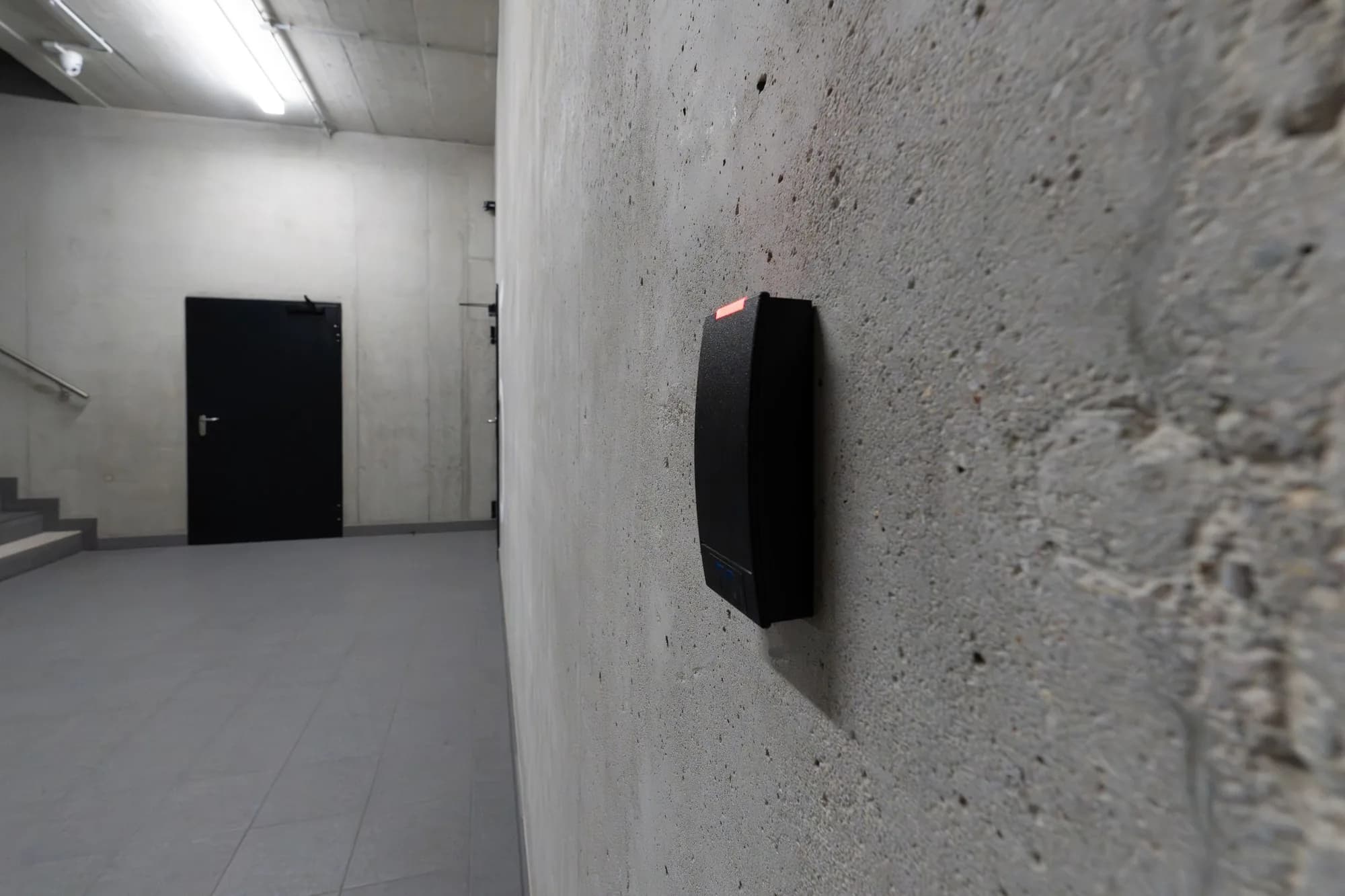 Access control card reader mounted on a concrete wall in a building corridor
